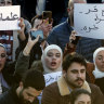 Syrian women chant slogans as they hold placards with Arabic that read: “No for free society without a free woman,” right, and “Secularism,” left, during a protest in December to demand a secular state.