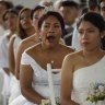 A bride yawns before the start a mass wedding the day before Valentine’s Day in Lima, Peru.