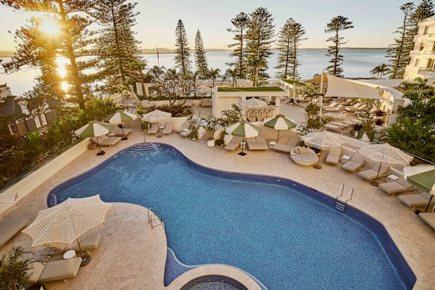 A hotel pool at sunrise with the beach in the background