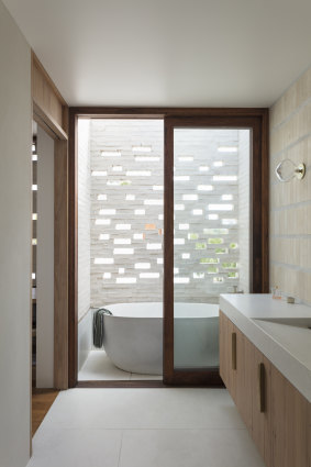 An outdoor bath, concealed behind a brick screen, provides a private place for bathing at Curl Curl House.