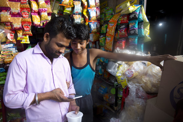 A man and youth watch election campaign ads on a phone in New Delhi in April.
