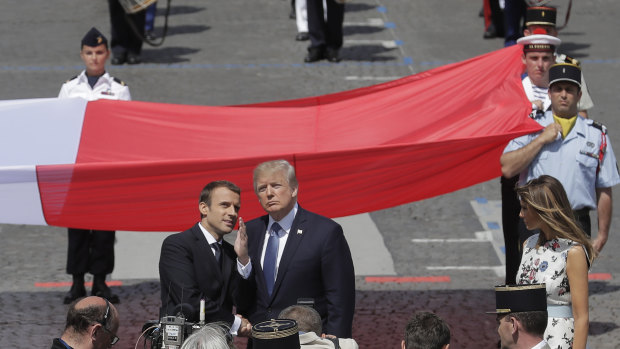 French President Emmanuel Macron talks with U.S President Donald Trump next to a huge French flag after the Bastille Day parade in Paris in  July.