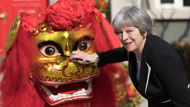 Theresa May dots the lion's eyes during a traditional lion dance ceremony outside the British embassy in Beijing.