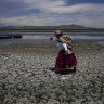 Maruja Inquilla walks on a dried out portion of Lake Titicaca in Coata, Peru, due to falling water levels amid a winter heat wave.