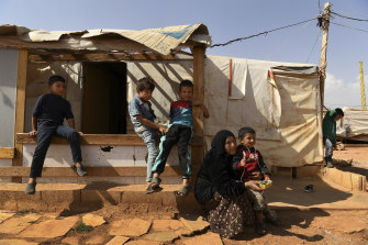 A woman sits with her grandson and other children in front of the temporary shelters in Saideh camp in the Bekaa Valley in Lebanon.