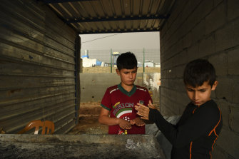 As winter approaches, Mustafa, 10, and Ahmed, 7, warm their hands over a barbecue at a kebab shop in Basirma refugee camp in Iraqi Kurdistan.