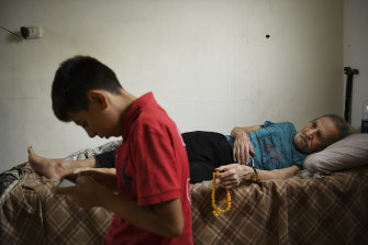 Syrian refugees Mohammad al-Deraai, 13, watched by his ill uncle Sobhi al-Deraai in the family apartment in Ain al-Hilweh.