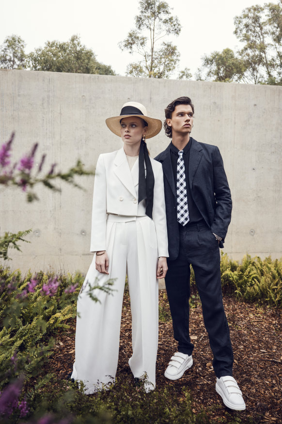 She wears Bianca Spender “Soho” jacket, $745, and “Procession” pants, $465; St Agni halter top, $329; Jasmin Sparrow “Amie” drop earrings in topaz/gold, $700; Sarah Curtis Panama hat, $329; Steve Madden heels, $130. He wears 
Nique “Kozo” jacket, $400, “Osakie” trousers, $190, and “Ryo” shirt, $300; Van Heusen tie, $40; Omega “Seamaster Diver 
300M 007 Edition” watch, $14,025; 
Zara sneakers, $70.