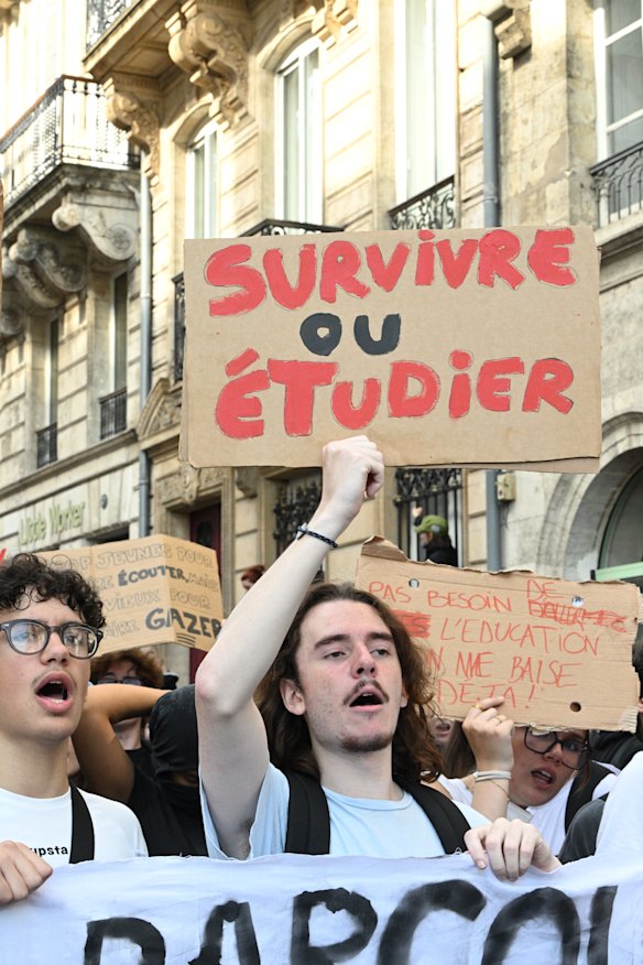 A student holds a board reading “surviving or studying” in Bordeaux.