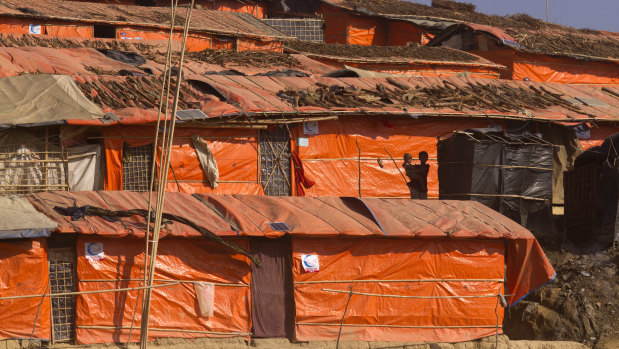 A Rohingya girl holds her brother while standing in front of their makeshift shelter at Jamtoli refugee camp in Cox's Bazar, Bangladesh.