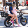Three girls ride on one e-bike in Manly. 
