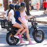 Three girls ride on one e-bike in Manly.