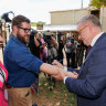 Anthony Albanese writes and signs a “No Change To WA GST” pledge on the arm of West Australian reporter Dylan Caporn in February 2024.