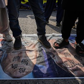 يقف المسلمون الشيعة فوق تمثيل لعلمي الولايات المتحدة وإسرائيل مع صور للرئيس دونالد ترامب ورئيس الوزراء بنيامين نتنياهو.