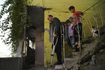 Wafa Gourani, 47, a dessert chef from Aleppo and now an amputee living in Istanbul, negotiates the steps from his apartment followed by his two youngest sons Hamza, 6, and Abdullah, 8.