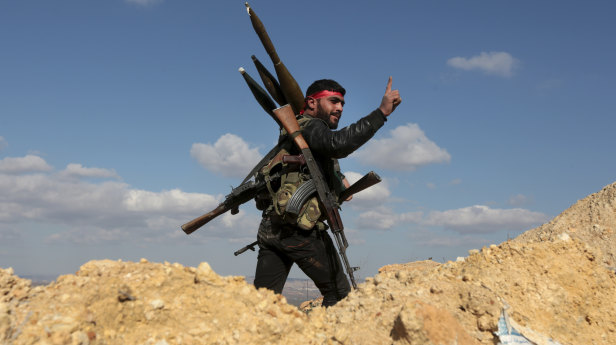 A pro-Turkey Syrian fighter waves on Bursayah hill, which separates the Kurdish-held enclave of Afrin from the Turkey-controlled town of Azaz, Syria.