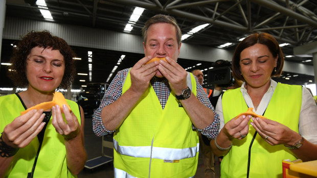 Queensland OppositIon Leader Tim Nicholls (centre), his deputy Deb Frecklington (right) and the LNP candidate for Miller Belinda Kippen eat a mango as they visit the Brisbane Markets on Friday.