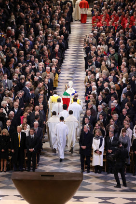Archbishop of Paris Laurent Ulrich (centre) leads clergy down the aisle of the cathedral.