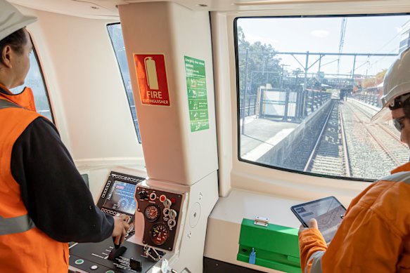 Metro staff during testing as a train passes through Lakemba.