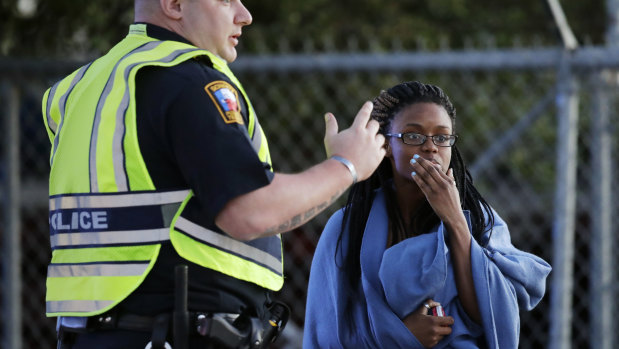 An employee wrapped in a blanket talks to a police officer after she was evacuated at a FedEx distribution center where a package exploded.
