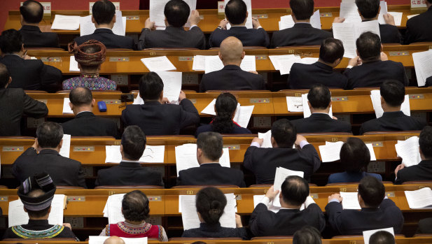 Delegates read paperwork before a plenary session of China's National People's Congress in Beijing.