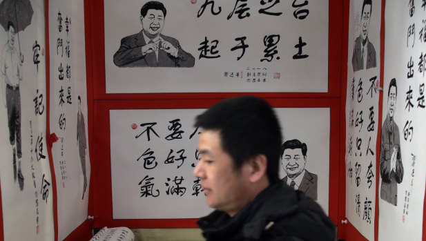 A man walks by posters featuring drawings of Chinese President Xi Jinping and his quotes, on display for sale at a market in Beijing.