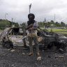 A man stands in front of a burnt car after unrest in Noumea, New Caledonia this week.