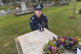 Leading Senior Constable Chris Trimble at murdered Senior Constable Edward Barnett's grave at Carisbrook Cemetery, with a replica of Barnett's Victoria Police Star.  