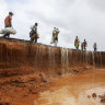 People walk on a destroyed section of the road following heavy rains which stopped vehicles from crossing along Mwingi-Garissa highway, Northern Kenya.