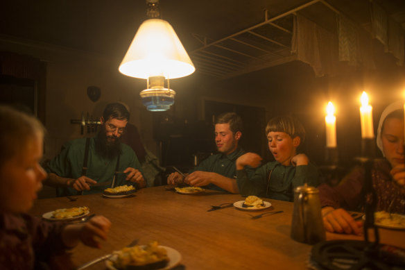 The McCallum family sits down to dinner by candlelight and  kerosene lamp.
