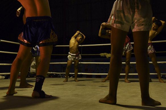 Samsun, 11, stretches with his fellow Muay Thai fighters at the Nor Naksin Muay Thai camp in Saraburi, Thailand, where he lives and trains. 