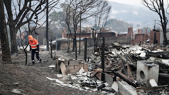 An electricity worker inspects properties on Wildlife Drive in Tathra after the bushfire.