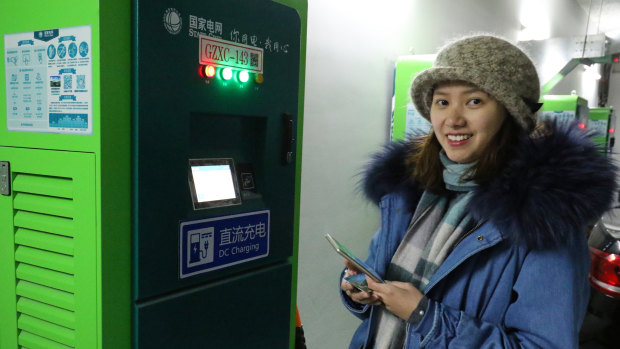 Young Beijing resident Dan Hong charges her new electric vehicle at a public charging station.