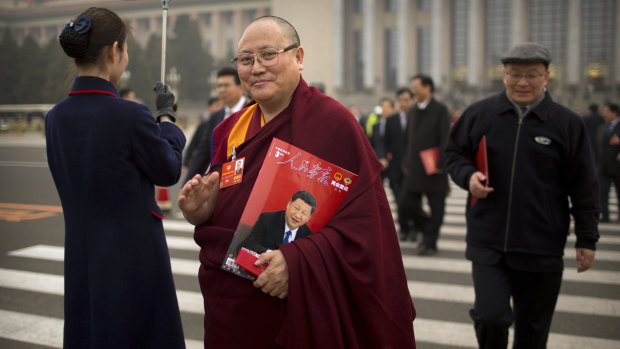 A delegate carries a magazine with a cover showing Chinese President Xi Jinping as he leaves the Chinese People's Political Consultative Conference.