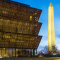 The National Museum of African American History and Culture at night with the Washington Monument in downtown Washington DC.