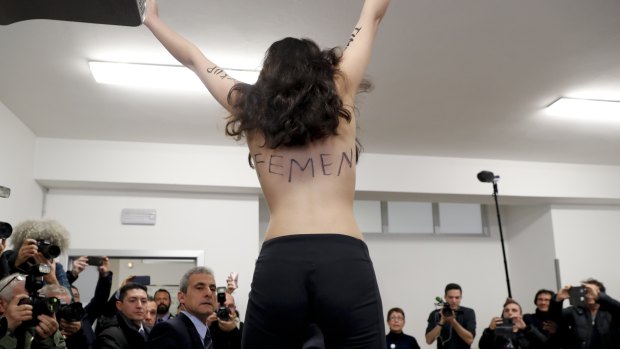 A topless Femen activist protests at a polling station where Silvio Berlusconi was about to vote, in Milan, Italy. 