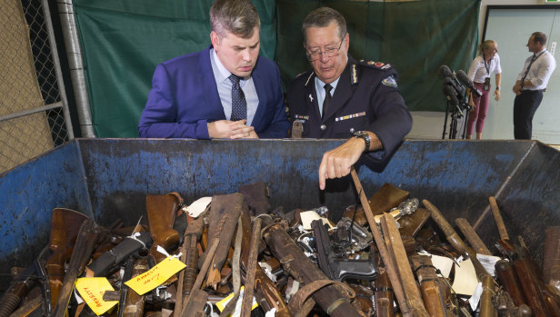 Police Minister Mark Ryan and Police Commissioner Ian Stewart inspecting some of the seized weapons, including rifles with scopes, shotguns and semi-automatic firearms.