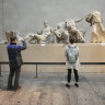 Visitors look at ancient sculptures that are part of the Parthenon Marbles at the British Museum in London.