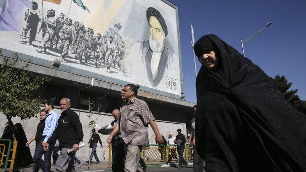  Iranian worshippers walk past a painting of the late revolutionary founder Ayatollah Khomeini and Basij paramilitary force members in Tehran.