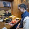 Servers lift the blinds to deliver dishes to solo diners.