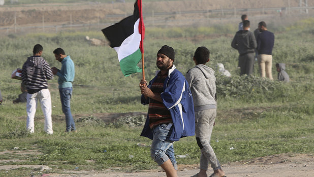 A protester waves his national flag during clashes with Israeli troops on the Israeli border with Gaza.
