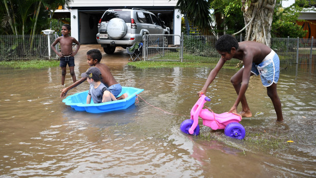 Children play in flood waters in Ingham on Sunday.