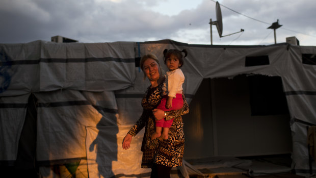 A Syrian woman carries a girl at the refugee camp of Ritsona about 86 kilometers north of Athens. 