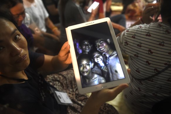 Thanaporn Promthep displays an image of her missing son Duangpetch (second right) and his coach “Ek” (right).