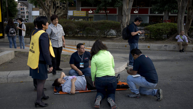 A woman is helped outside, along Reforma Avenue after a 7.2-magnitude earthquake shook Mexico City.