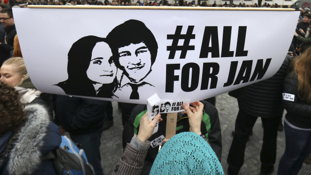 A woman sticks a sticker on a poster with a photo of slain journalist Jan Kuciak and his fiancee Martina Kusnirova, during an anti-government rally in Bratislava, Slovakia, Friday.