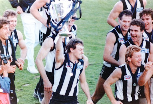 Mick McGuane holds the premiership cup aloft during the traditional lap of honour with teammates.