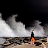 A person walks past large breaking waves at Clovelly beach on Saturday morning. 