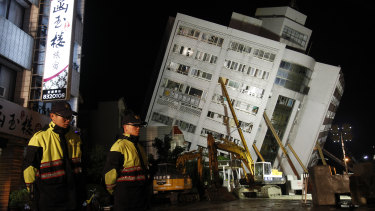 Two police officers guard outside of a collapsed apartment building in Hualien County, eastern Taiwan.