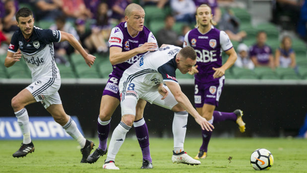 Tight defence: Perth's Shane Lowry applies pressure to Melbourne striker Besart Berisha.
